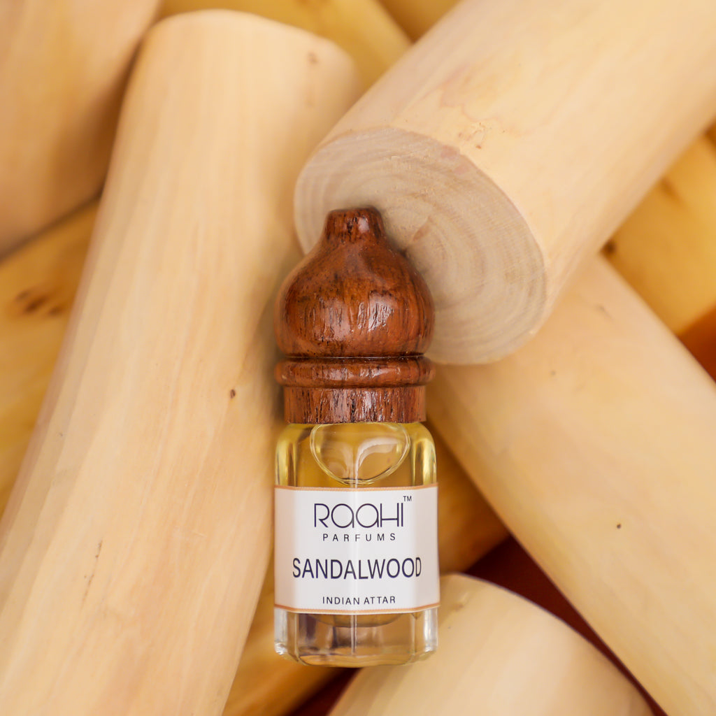 A small clear glass bottle of golden-yellow sandalwood attar with a polished wooden cap handcrafted in kannauj