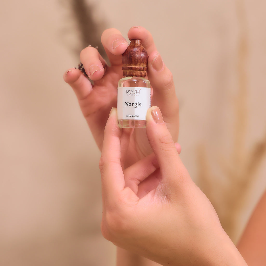 A small clear glass bottle with wooden dropper cap labeled nargis handcrafted fragrance by roch parfums from Kannauj