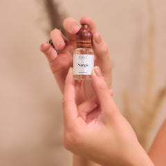 A small clear glass bottle with wooden dropper cap labeled nargis handcrafted fragrance by roch parfums from Kannauj