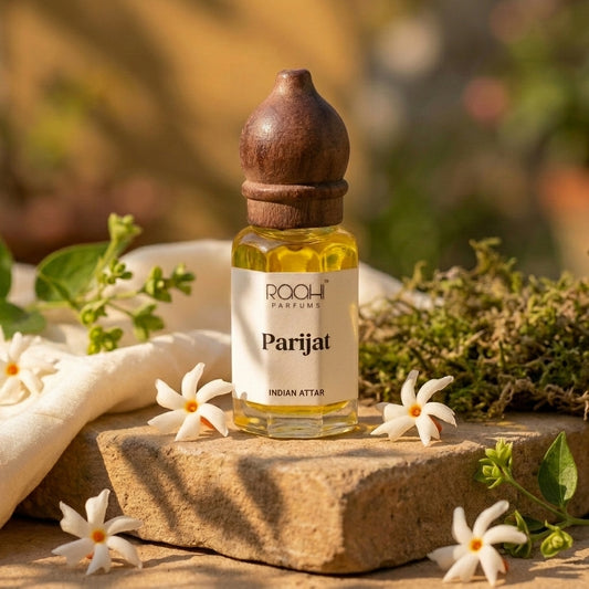 A small clear glass bottle with a dark brown wooden stopper containing golden-yellow parijat attar by roohi parfums