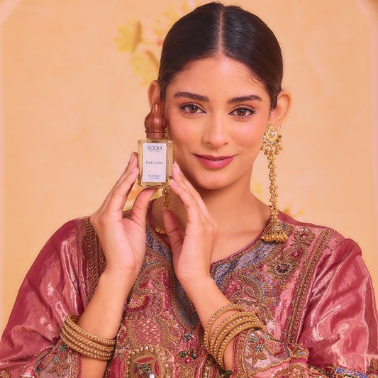 A sleek transparent glass bottle with a golden cap labeled roch pink luxe holds pink lotus eau de parfum 50ml