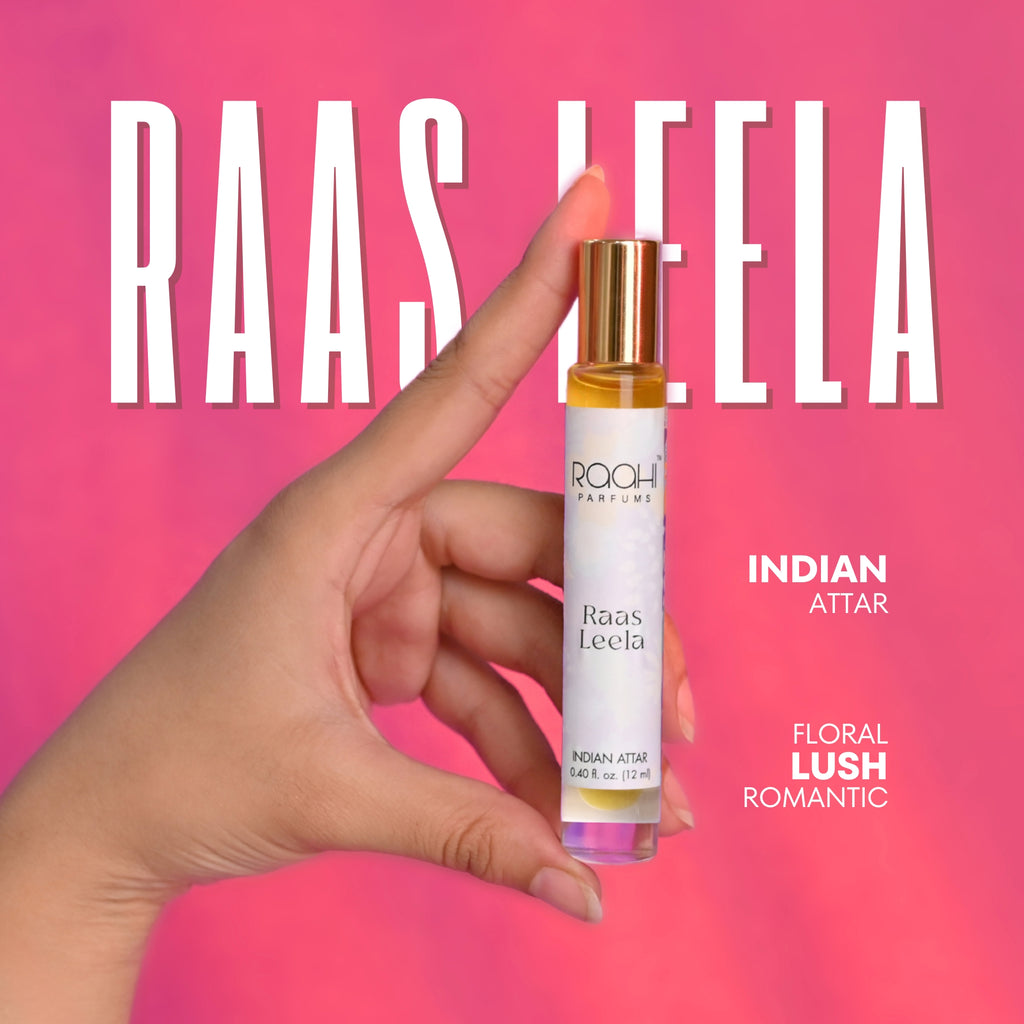 A sleek transparent glass rollerball bottle with a gold cap containing amber indian attar perfume raas leela by raahi parfums