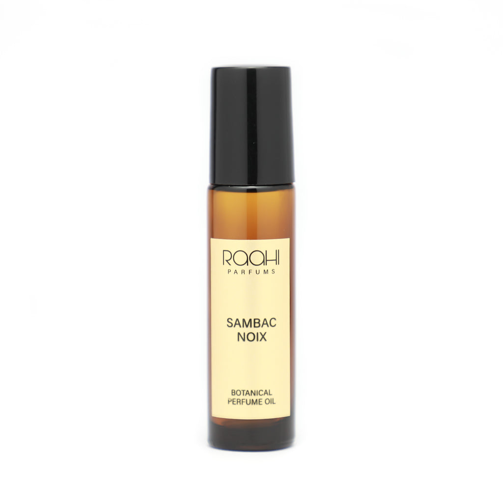A sleek amber glass rollerball bottle with black cap and cream label of roohi parfums sambac noix botanical perfume oil