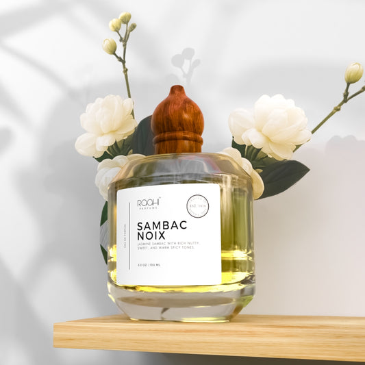 A clear glass bottle with a wooden stopper, labeled ’sambac noix’ by roahi perfume.