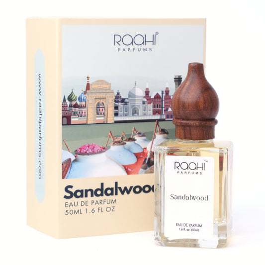 A clear glass bottle of raahi parfums sandalwood eau de parfum 50ml with a dark brown wooden stopper and white label