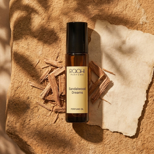A sleek amber glass rollerball bottle with black cap and cream label of raoi parfums sandalwood dreams perfume oil
