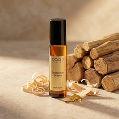 A sleek amber glass rollerball bottle of raahi parfums sandalwood dreams perfume oil with black cap and gold label