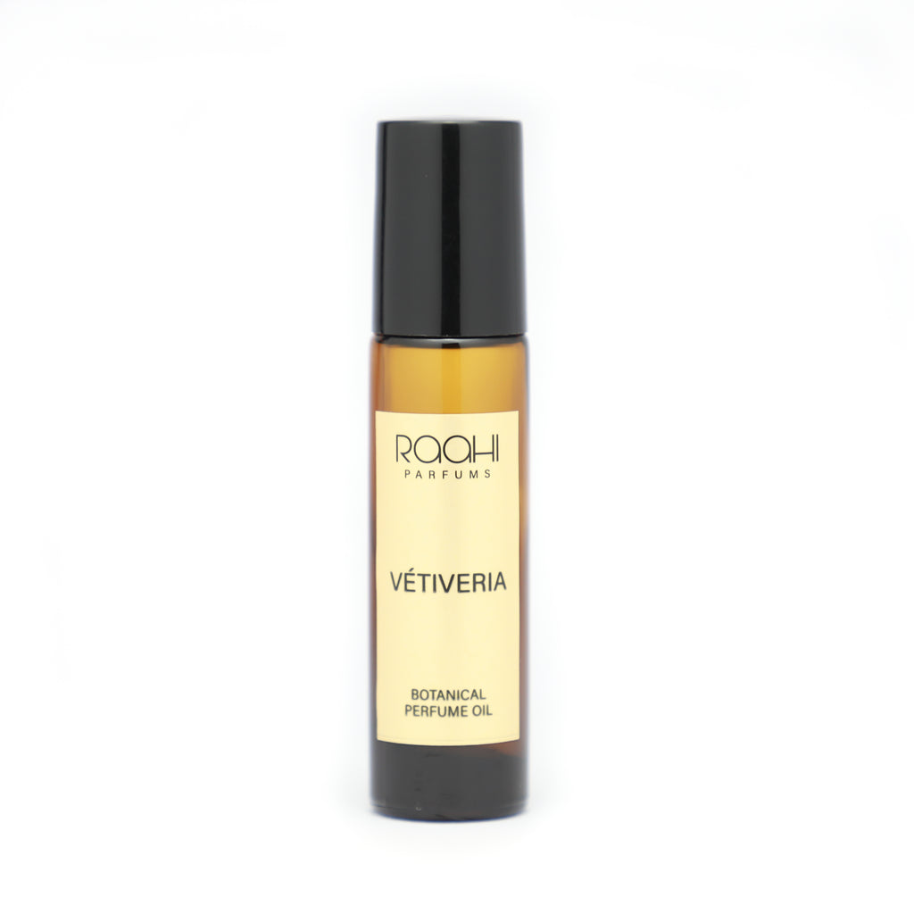 A sleek amber glass rollerball bottle with black cap and cream label of roohi parfums vétiveria botanical perfume oil