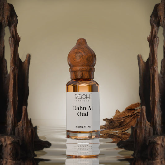 A sleek amber glass bottle of raahi parfums dahn al oud Indian attar with a hand carved wooden stopper and label