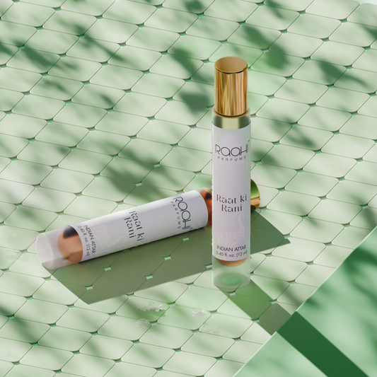 A sleek white rollerball perfume bottle with gold cap labeled roohi parfums raat ki rani indian attar 12ml